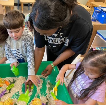 BCCS Teacher's Aide Sydney Ambrose works with students at a sensory table.
