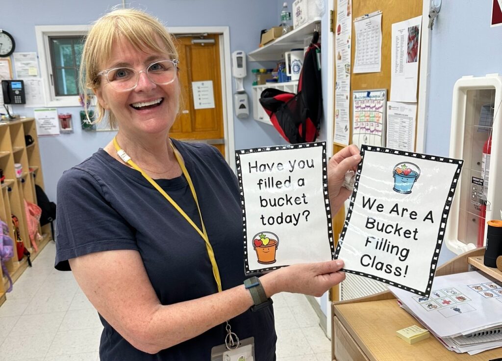 A BCCS teacher poses with the Bucket Filler artwork