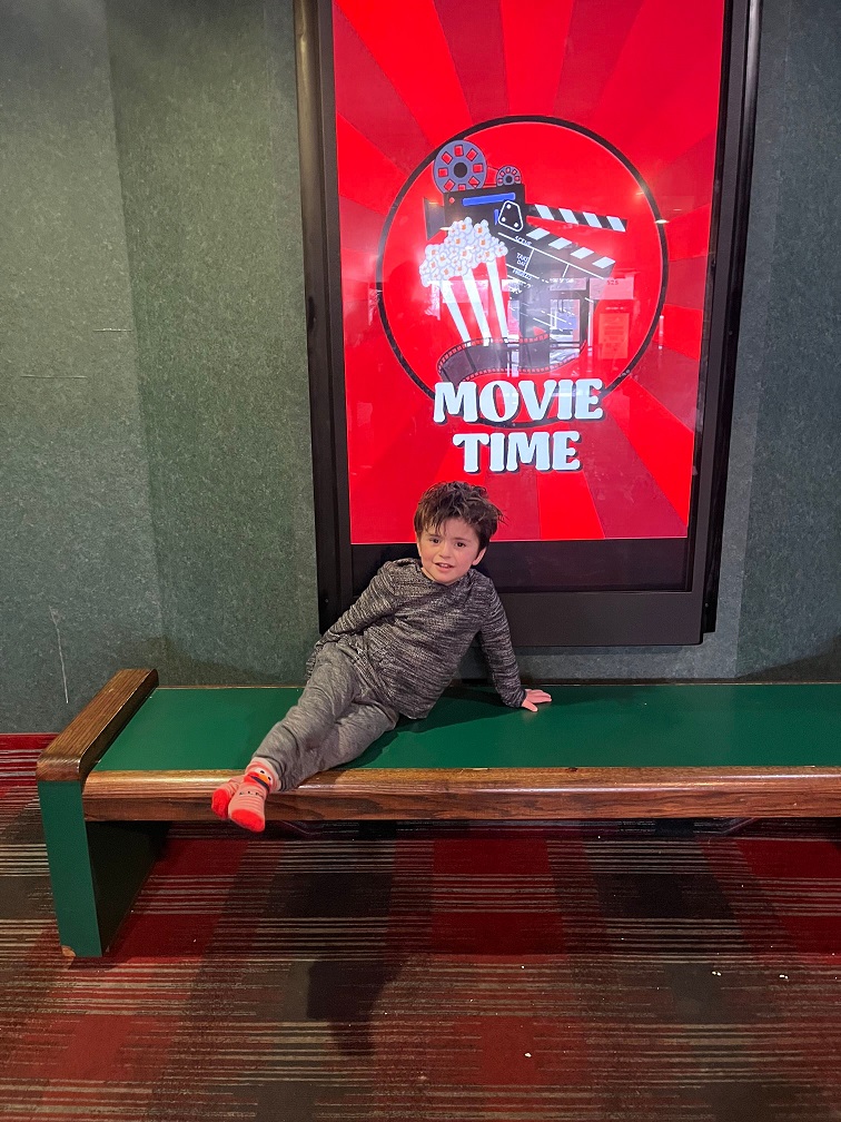 A Barbara C. Wilson student in front of a sign that says "Movie Time"