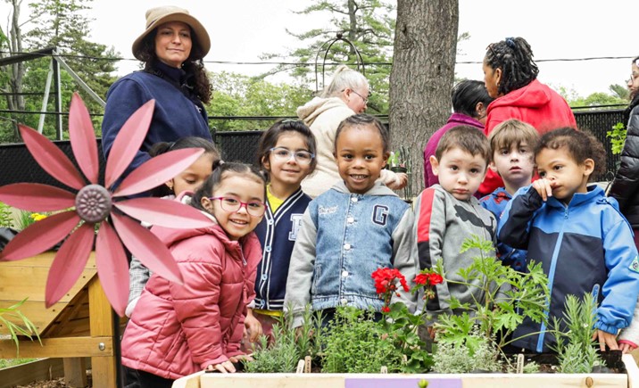 A group of BCCS students and teachers gather around some plants in the sensory garden.