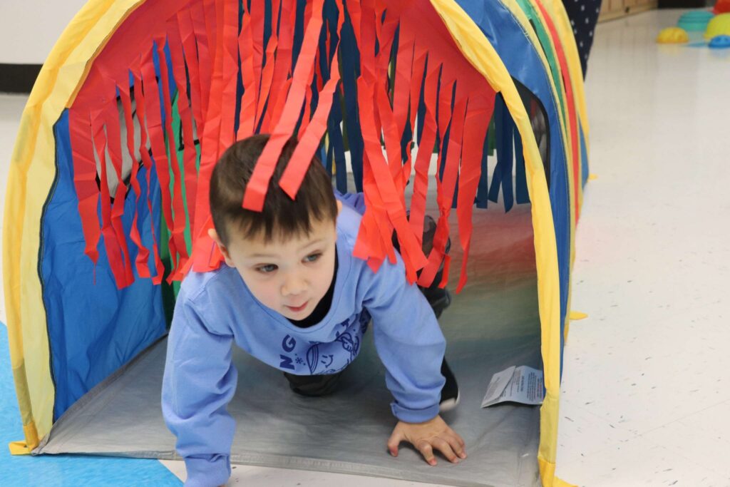 A BCW students crawls through a tube in the Winter Olympics obstacle course.