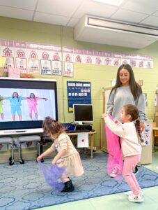 A teacher and students dance with scarves during Preschool exchange.