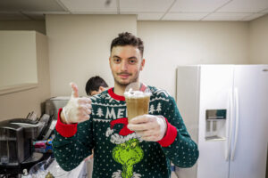 A BCCS student holds a cup of coffee he made and gives a thumbs up.