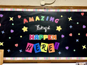 Classroom decoration reads "Amazing things happen here!" in colorful lettering.
