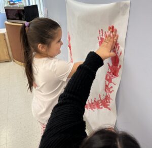 A Post Avenue Preschool student creates handprint art for Wear Red Day