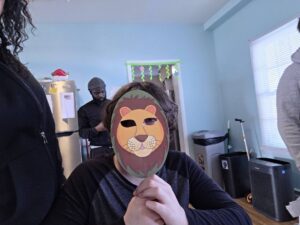 A Children's Residential Program resident holds up a lion mask to his face to celebrate Passover.