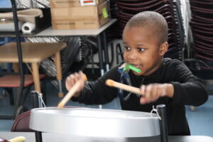 A Children's Education Center student plays the drums.