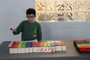 A Children's Education Center student plays the xylophone.