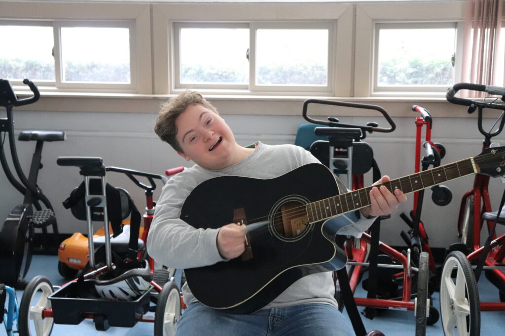A Children's Education Center student plays the guitar.