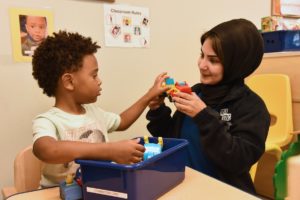 a student and teacher playing with trucks