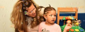 teacher and girl playing with bubbles