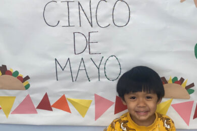 A student poses in front of a Cinco de Mayo poster