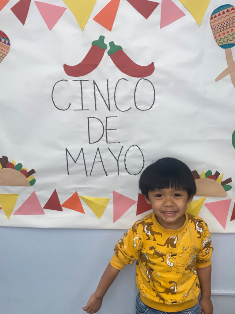 A student poses in front of a Cinco de Mayo poster