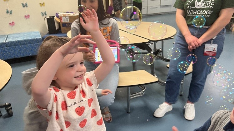 A student plays with bubbles for Better Hearing and Speech Month