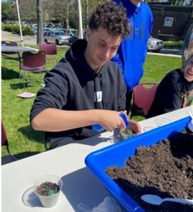 A student puts put into a cup for his Earth Day project