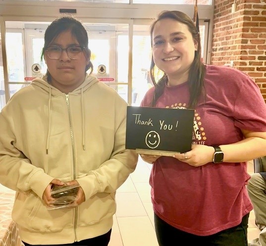Children’s Education Center students with a sign they created for their snack cart that reads "Thank you!"