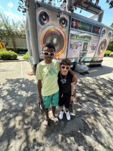 Two students pose together in front of the bouncy house at the carnival.