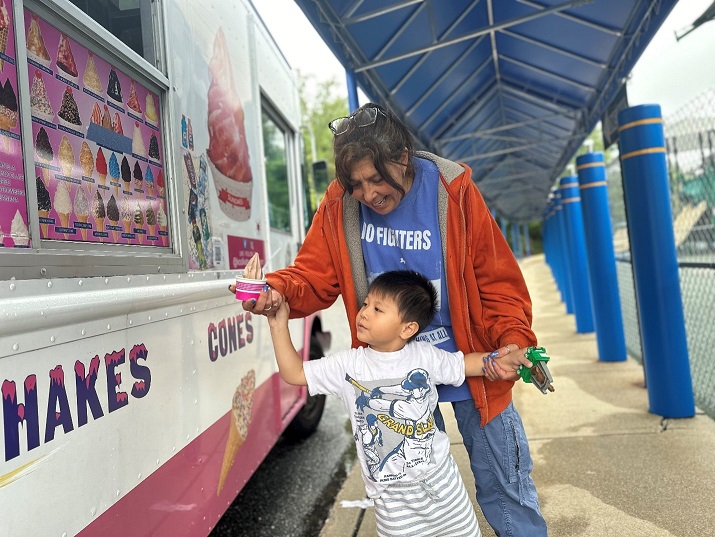 A Barbara C. Wilson Preschool teacher and student receive ice cream from the ice cream truck.