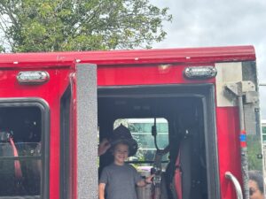 A BCCS student wears a firefighter's helmet inside a firetruck at the touch-a-truck event