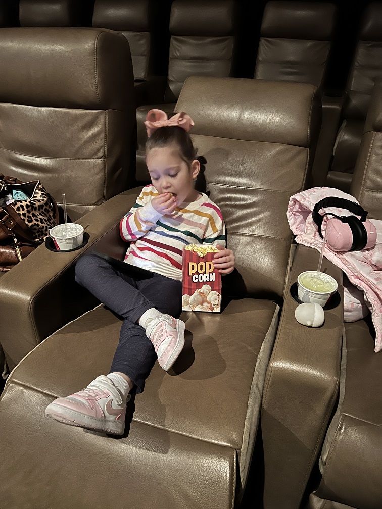 A Barbara C. Wilson student eating popcorn in a movie theatre seat