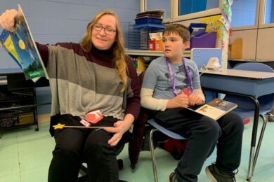 A child supported by the BCCS Home & Community Program reads with a teacher.