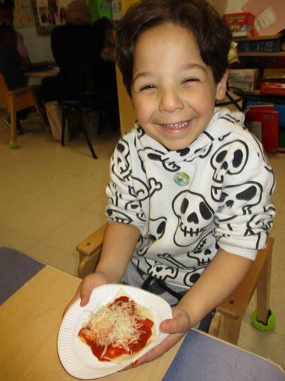 A BCCS preschool student with the pizza he made during Food Week.