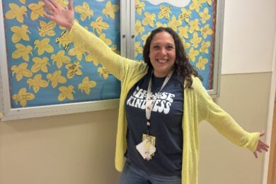Marcus Avenue Preschool Social Worker Lisa Kaplan in front of her "Bee Positive" board