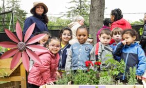 A group of BCCS students and teachers gather around some plants in the sensory garden.