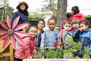 A group of BCCS students and teachers gather around some plants in the sensory garden.