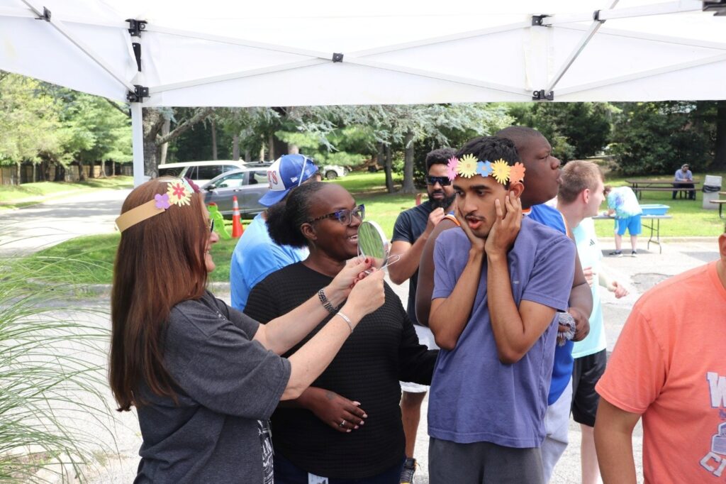 A Children's Education Center staff member shows a student the flower crown he made in the mirror.