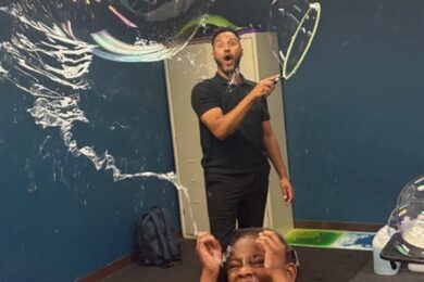 Bubbleologist Daniel Garcia makes bubbles while a Marcus Avenue student laughs.