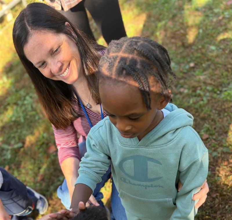 A Post Avenue teacher helps a student pet an animal.
