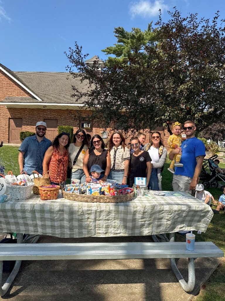 The Barbara C. Wilson Preschool Fathers' Group pose behind a picnic table.