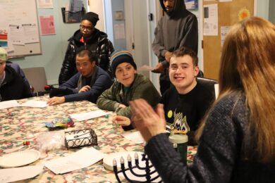 Young men supported by the Children’s Residential Program listen to Deborah Lapidus teach about Chanukah.