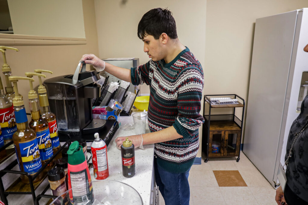 A student working at Brookville Beans works the coffee machine.